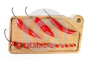 Wooden board with red pepper cut into slices hot sauce with copy space white background