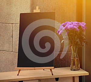 Wooden board for restaurant menu with empty space to add text standing at restaurant entrance with flower pot