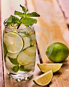 On wooden boards is glass with mohito and lime.