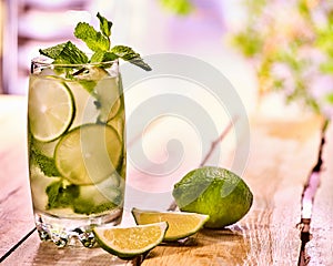 On wooden boards is glass with mohito and lime.