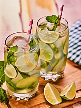 On wooden boards is glasses with mohito and napkin.