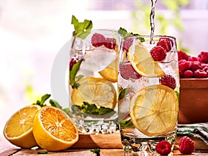 On wooden boards is glasses with raspberry mohito and jug.