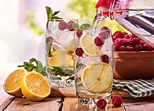 On wooden boards is glasses with raspberry mohito and jug.