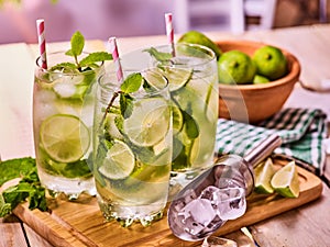 On wooden boards three glasses with mohito and lime.