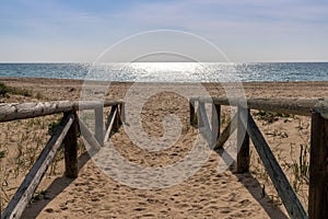 Wooden boardwalk and beach access leads directly onto beach with glistening calm ocean behind photo