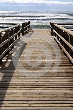 Wooden boardwalk and beach access leads directly onto beach with stormy waves and skies