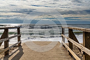 Wooden boardwalk and beach access leads directly onto beach with stormy waves and skies