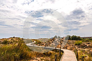 Wooden boardwalk in the dunes leading to the sandy beach, the pa