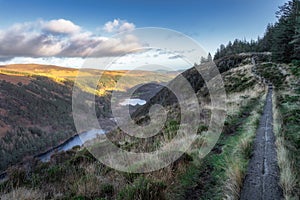 Wooden boardwalk on the top of a mountain with a view on Glendalough lakes and forest. Wicklow Mountains, Ireland