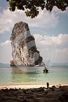 Wooden boat arriving on beach with rocky cliff photo