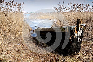 The wooden boat on the bank of the lake in the early spring