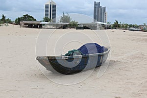 wooden boat with blue fish net lay  a beach side