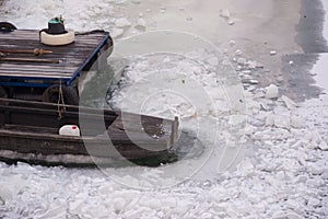 Wooden boat and dock in frozen river on cold winter day