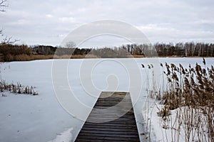 Wooden boat dock on a frozen winter lake.