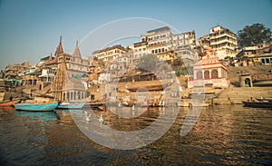 Colorful wooden boats docked along the shore of the Ganges River, at one of the many ghats in Varanasi, India.