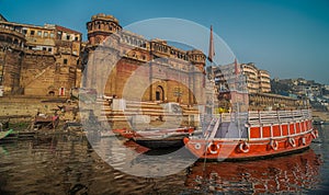 Colorful wooden boats docked along the shore of the Ganges River, at one of the many ghats in Varanasi, India.