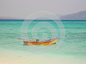 Wooden boat floating on sea at beach light blue beac at Havelock Island