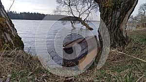 Di legno una barca legato secondo catena sul erboso Banca salici crescente sul un trasformato su giù. foresta rack sul opposto 