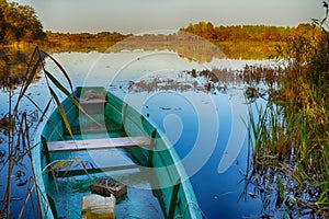 The wooden boat moored on lake ashore in Russian rural nature