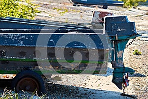 A wooden boat with a motor is parked on land. The old boat is on the rocks. Wooden motor boat. The old boat is on the shore