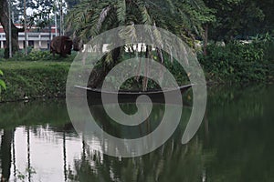 The wooden boat parked in the bank of pond in a village