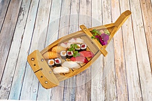 Wooden boat with passengers of Japanese sushi assorted from mantiquilla fish nigiri, red tuna, Norwegian salmon, makis with rice photo