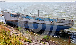 Broken boat shipwreck washed ashore after sea crossing photo
