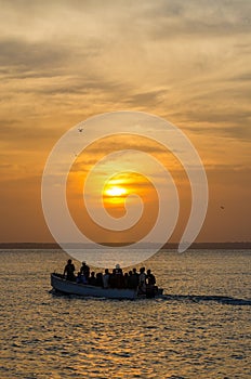 Wooden boat with unidentifiable people and beautiful sunset over sea, Bubaque, Bijagos islands, Guinea Bissau, Africa