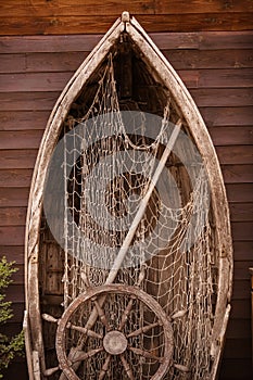 Wooden boat wall composition with fishing net andvitage ship`s wheel helm. Art desing