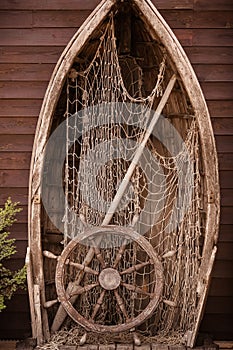 Wooden boat wall composition with fishing net andvitage ship`s wheel helm. Art desing