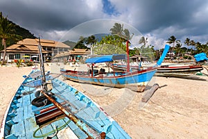 Wooden boats of Asia on the sandy beach of the resort.