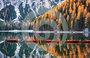 Wooden boats in Braies lake at sunrise in autumn in Dolomites