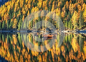 Wooden boats in Braies lake at sunrise in autumn in Dolomites