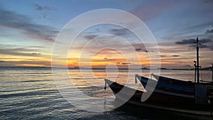 Wooden boats docked at a beach near an island at sunset