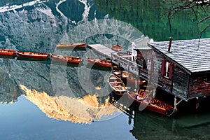 Wooden boats and house on Lake Braies, Dolomites, Italy. Reflection of mountains