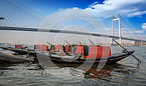 Wooden boats lined up on Hooghly river bank overlooking Vidyasagar bridge Setu.