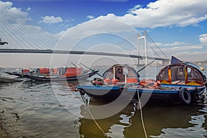 Wooden boats lined up on Hooghly river bank with Vidyasagar bridge Setu at the backdrop