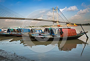 Wooden boats lined up on river Hooghly at Princep Ghat with Vidyasagar bridge (setu) at the backdrop