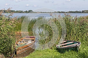 Wooden boats, old fishing vessels on the coast of tranquil lake, sustainable ecological tourism in Europe