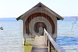 Wooden boatshed on the lake with narrow passage bridge