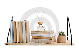 Wooden book shelf with flowerpot and reed diffuser on white background