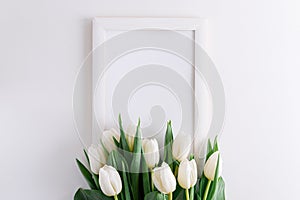 Wooden border decorated bouquet of white tulips on white background. Anniversary celebration concept. Soft focus