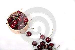 Wooden bowl of black cherries isolated on white background flat lay