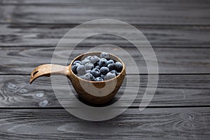 Wooden bowl with blueberries on black table