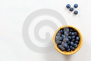Wooden bowl of blueberries on side of white background
