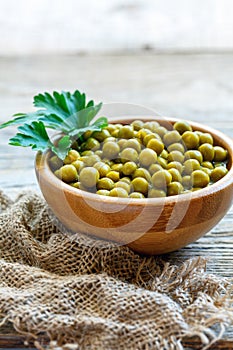 Wooden bowl with canned green peas.