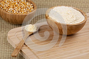 Wooden bowl of cornmeal or cornflower on a wooden background