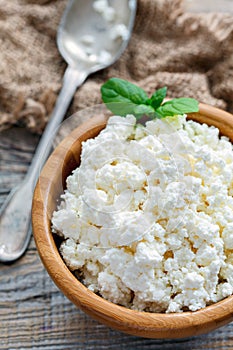 Wooden bowl with cottage cheese and mint.