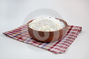 Wooden bowl with cottage cheese on the white table
