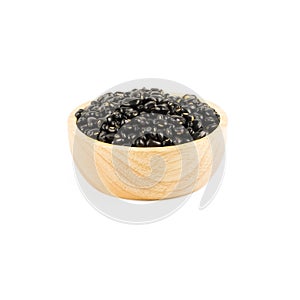 Wooden bowl of dry black beans isolated on white